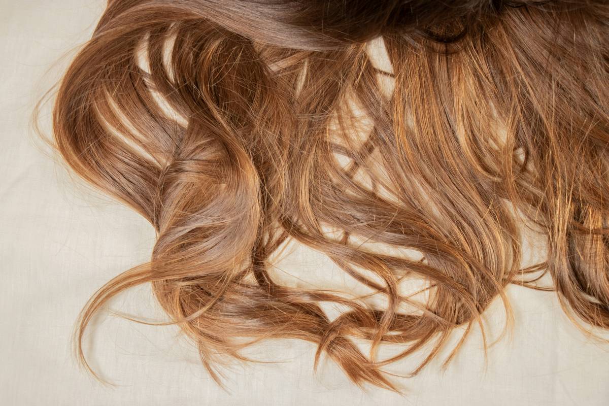Close-up of hand applying anti-frizz hair gel to damp curly hair to control frizz and enhance definition
